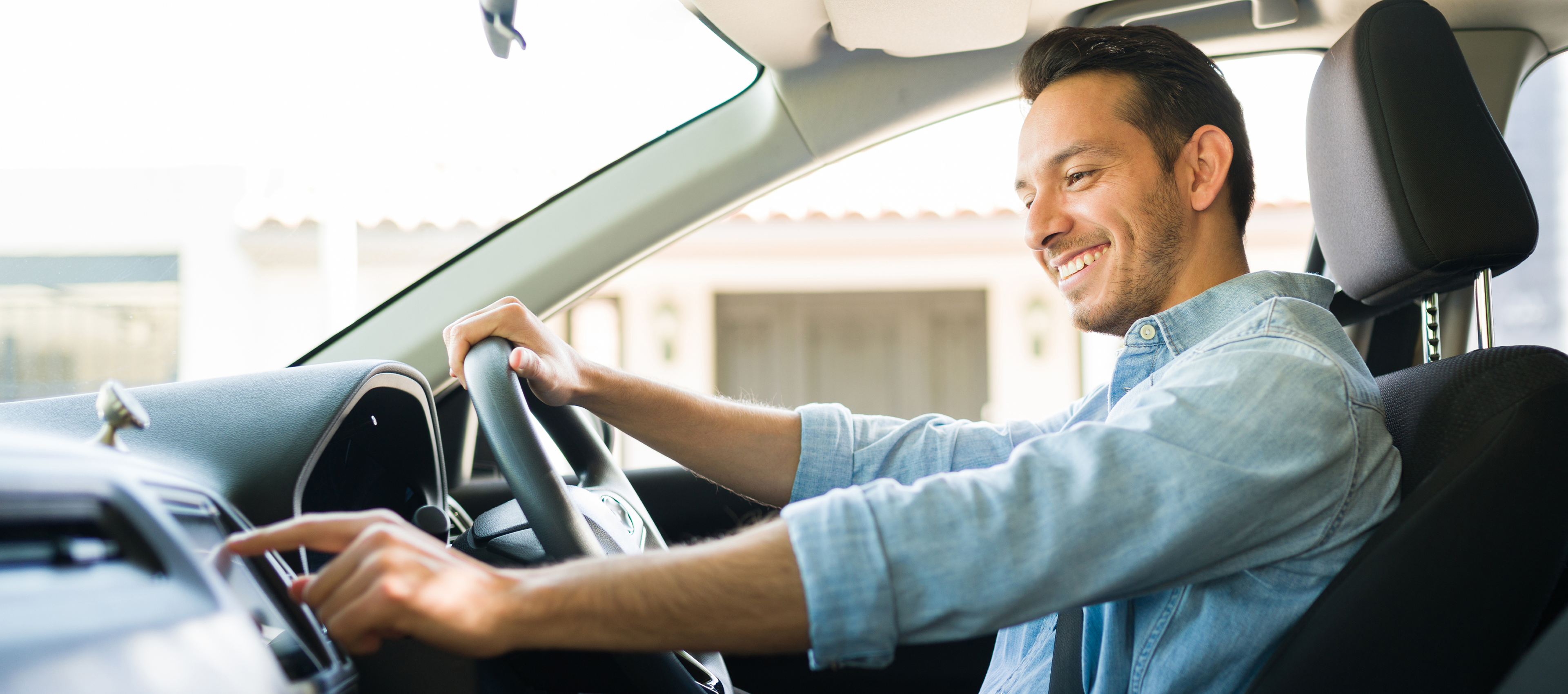 Man smiling while adjusting car controls.