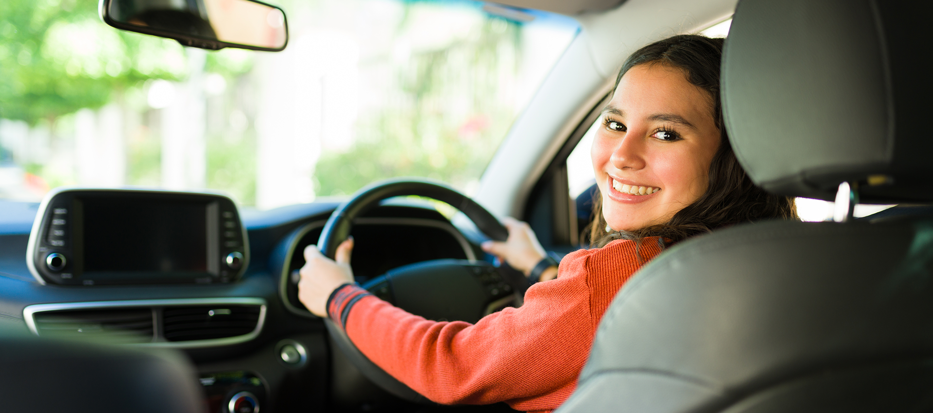 Smiling woman driving a car confidently.